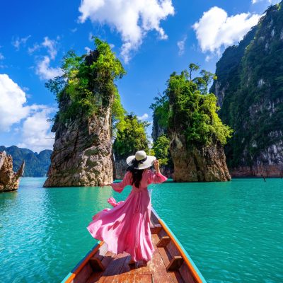 beautiful girl standing on the boat and looking to mountains in